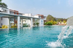 A modern hotel with a swimming pool, outdoor seating, and a waterfall feature. - El Arbol by Hireavilla-2br w Rooftop Pool in Nerul (Nerul)