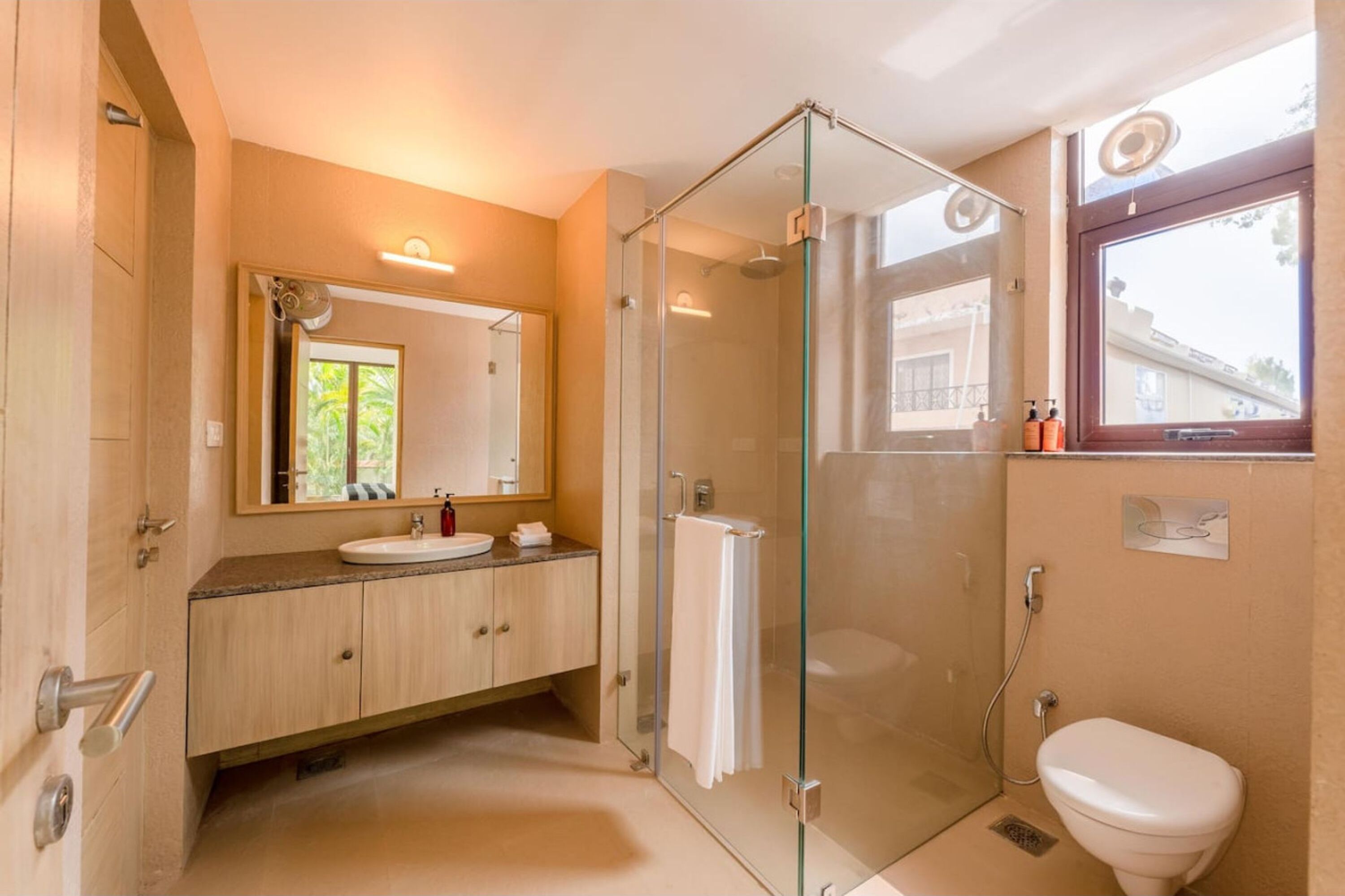 A modern bathroom with a glass-enclosed shower, a sink with a mirror, and a toilet.