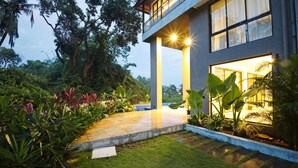 A modern house with a balcony, surrounded by lush greenery and a well-maintained garden. - Cozy 1BR With Pool - Only 1km From Candolim Beach (Candolim)