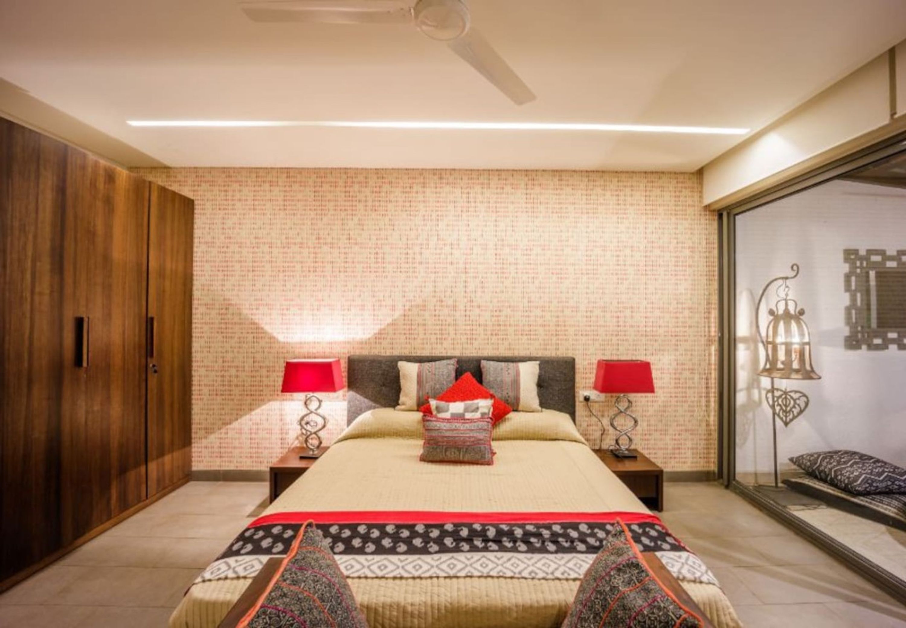 A bedroom with a bed, two bedside tables, a wardrobe, and a large window with a view.