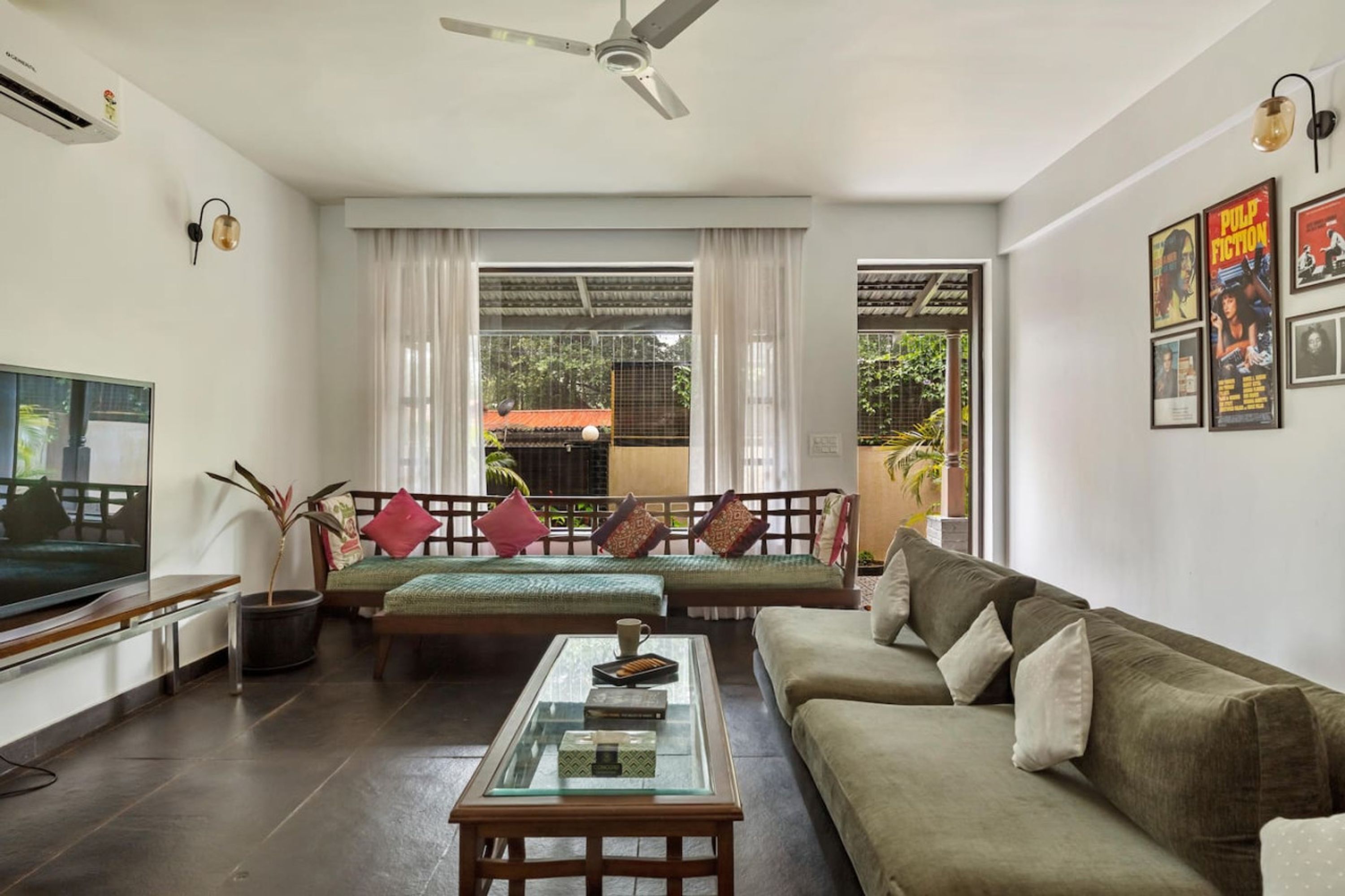 A living room with a sofa, a glass coffee table, a television, and a ceiling fan.