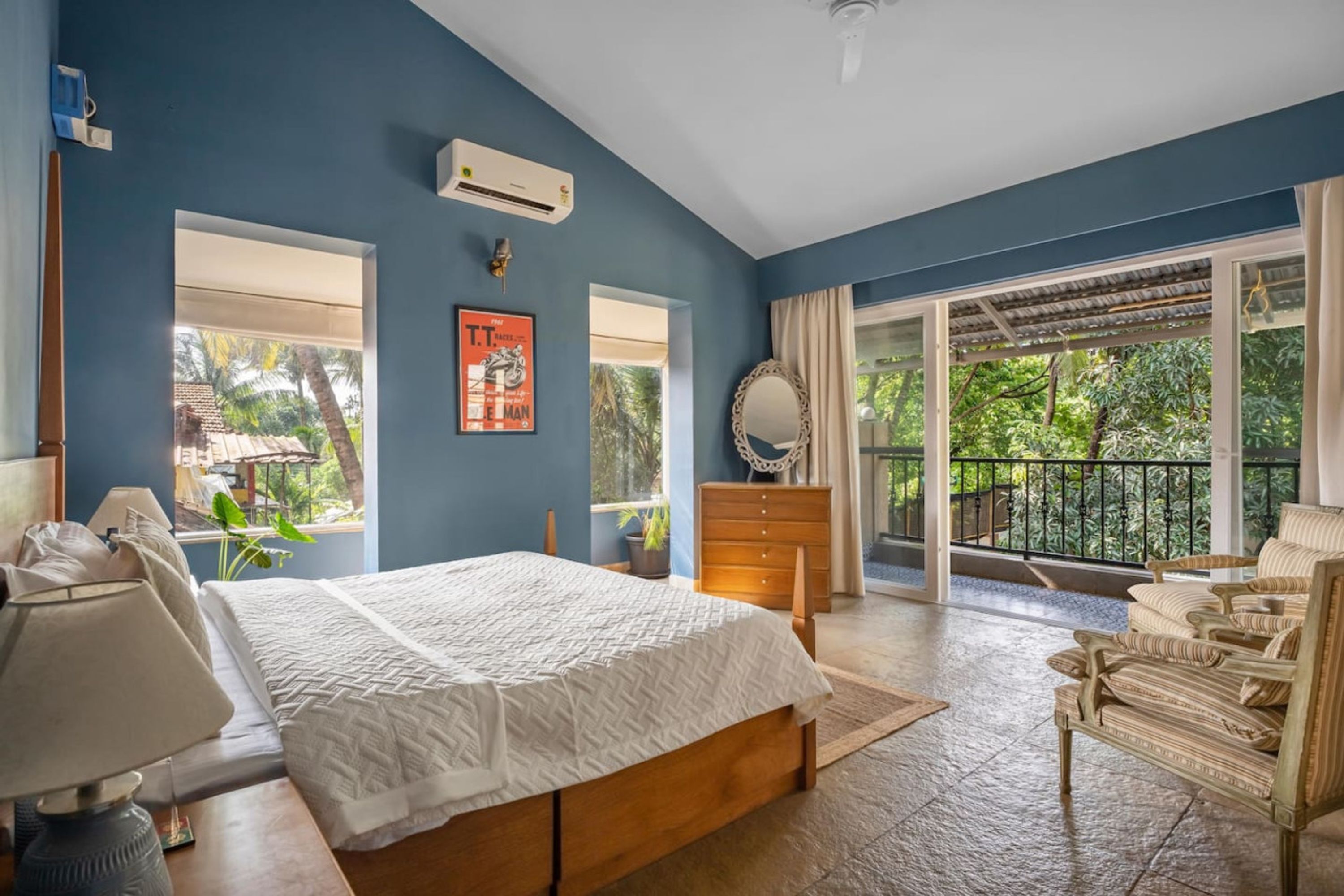 A bedroom with a bed, a dresser, a chair, and a large window.