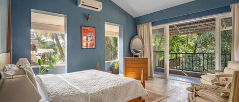 A bedroom with a bed, a dresser, a chair, and a large window.