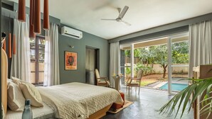 Un dormitorio moderno con una cama grande, ventilador de techo y vistas a una piscina y jardín.
