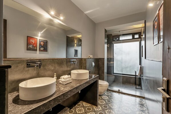 Un baño moderno con dos lavamanos, un espejo grande y una zona de ducha.