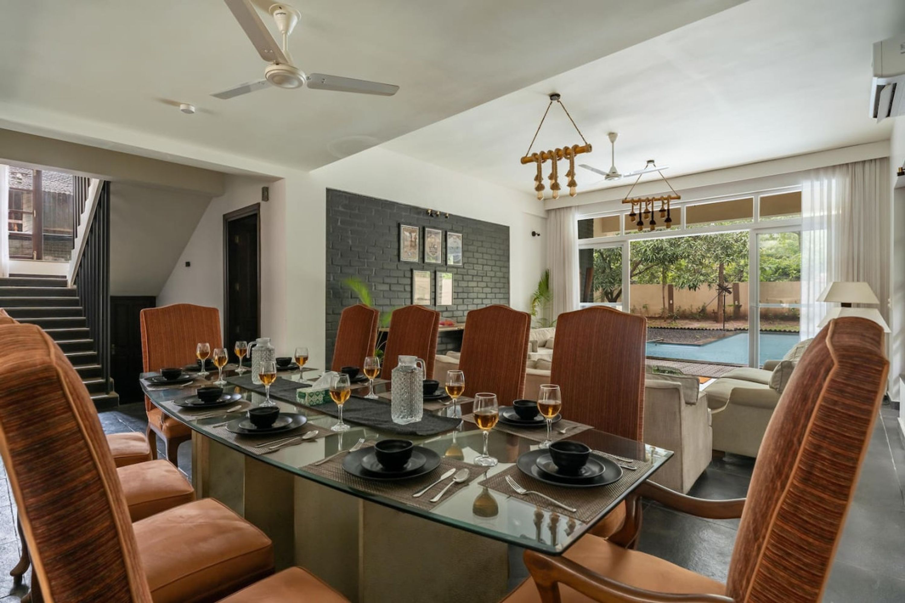 A dining area with a glass table, brown leather chairs, and a view of a swimming pool.