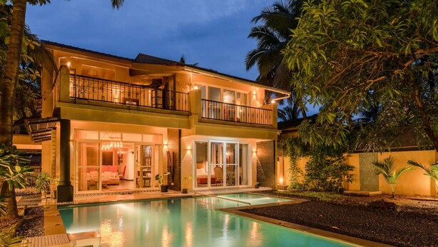 Una casa de dos pisos con piscina, balcón y un interior bien iluminado.