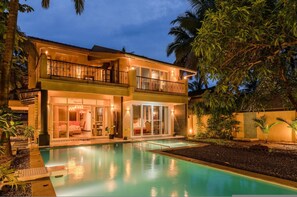 Una casa de dos pisos con piscina, balcón y un interior bien iluminado.