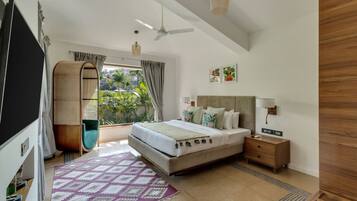 A modern bedroom with a large bed, a bedside table, a TV, and a view of greenery outside.