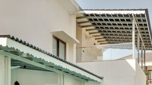 Una casa moderna con piscina, un patio coperto con divano e poltrone, e un'ampia porta in vetro che dà sull'interno.