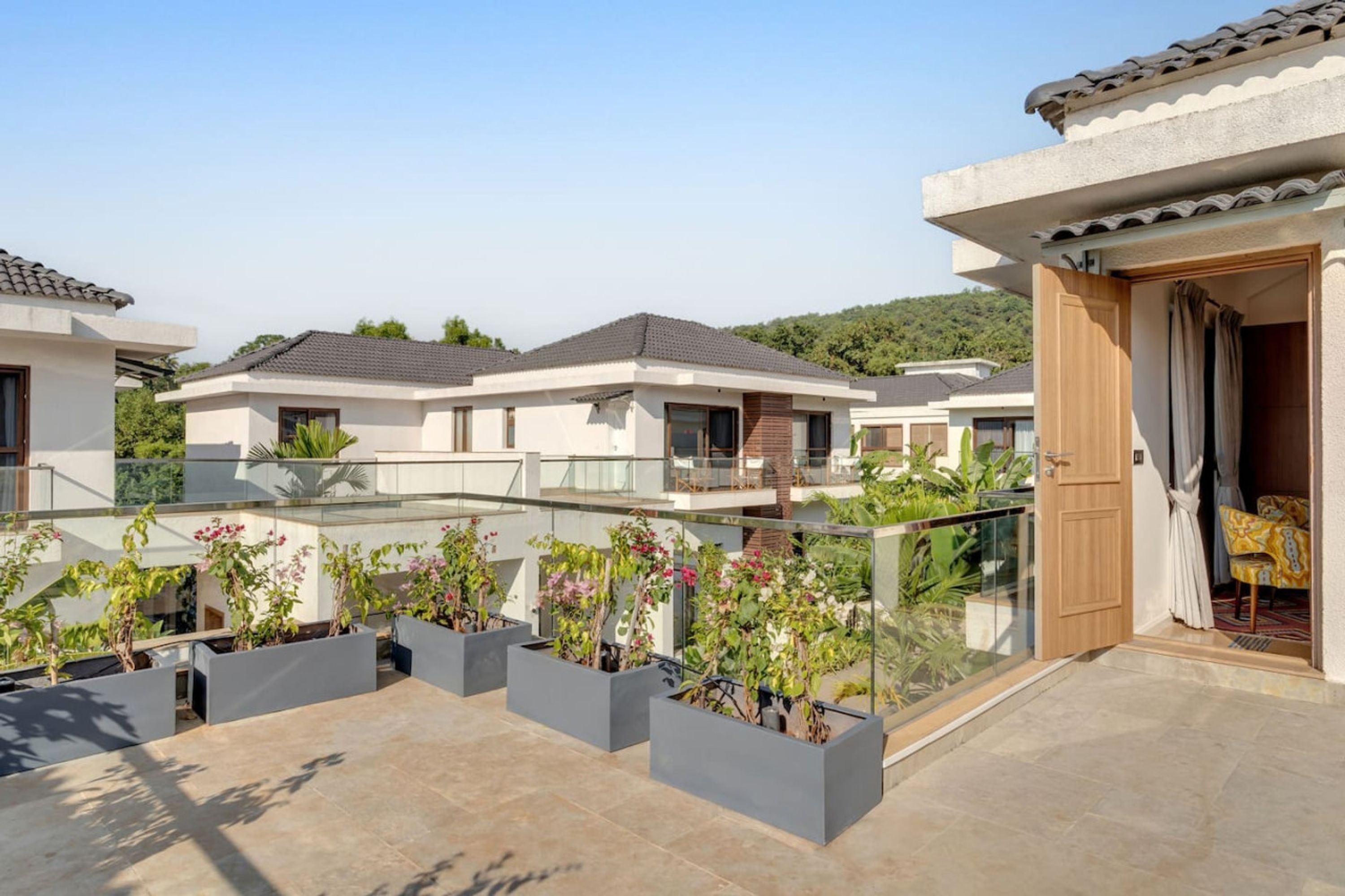 A residential building with a balcony, potted plants, and a wooden door.