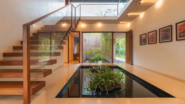 A modern interior with a glass staircase, a central water feature, and framed artwork on the walls. - Puravida I -luxury 5bhk w Pvt Pool in Anjuna (Anjuna)
