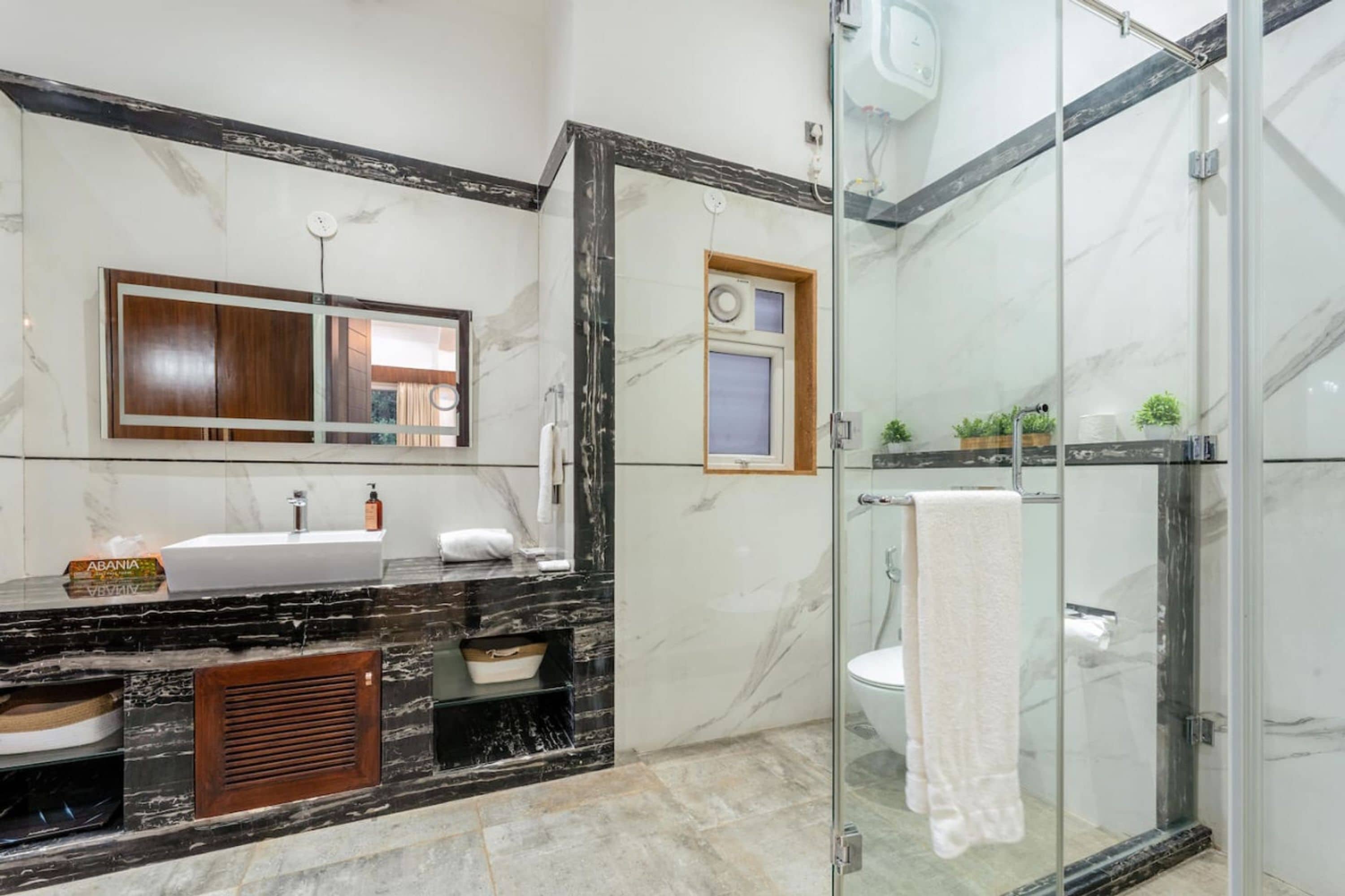 A modern bathroom with a glass-enclosed shower, a marble sink, and a large mirror.