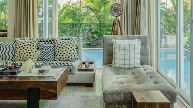 A spacious living area with a large window, a ceiling fan, and a view of a swimming pool. - Luxe 3bhk w Private Pool Assagao Casa Rehmyra (Assagao)
