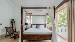 A four-poster bed with a wooden frame, white bedding, and a view of greenery through the window. - Luxe 3bhk w Private Pool Assagao Casa Rehmyra (Assagao)