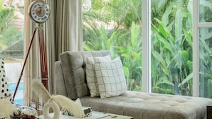 A cozy seating area with a cushioned bench, a wooden coffee table, and a tripod lamp. - Luxe 3bhk w Private Pool Assagao Casa Rehmyra (Assagao)