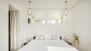A hotel room with a large bed, white walls, a ceiling fan, and a mirror above the bed. - Nova by Hireavilla - 2BR w Private Pool in Anjuna (Vagator)