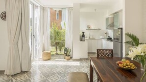 A modern kitchen with white cabinets, a stainless steel refrigerator, and a dining area with a wooden table and chairs. - Nova by Hireavilla - 2BR w Private Pool in Anjuna (Vagator)