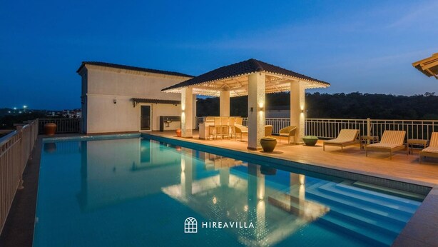 A rooftop pool with a covered seating area, a modern building, and a clear view of the surrounding landscape. - Luxe Apt w Balcony Rooftop Pool 15 min to Beach (Marra)