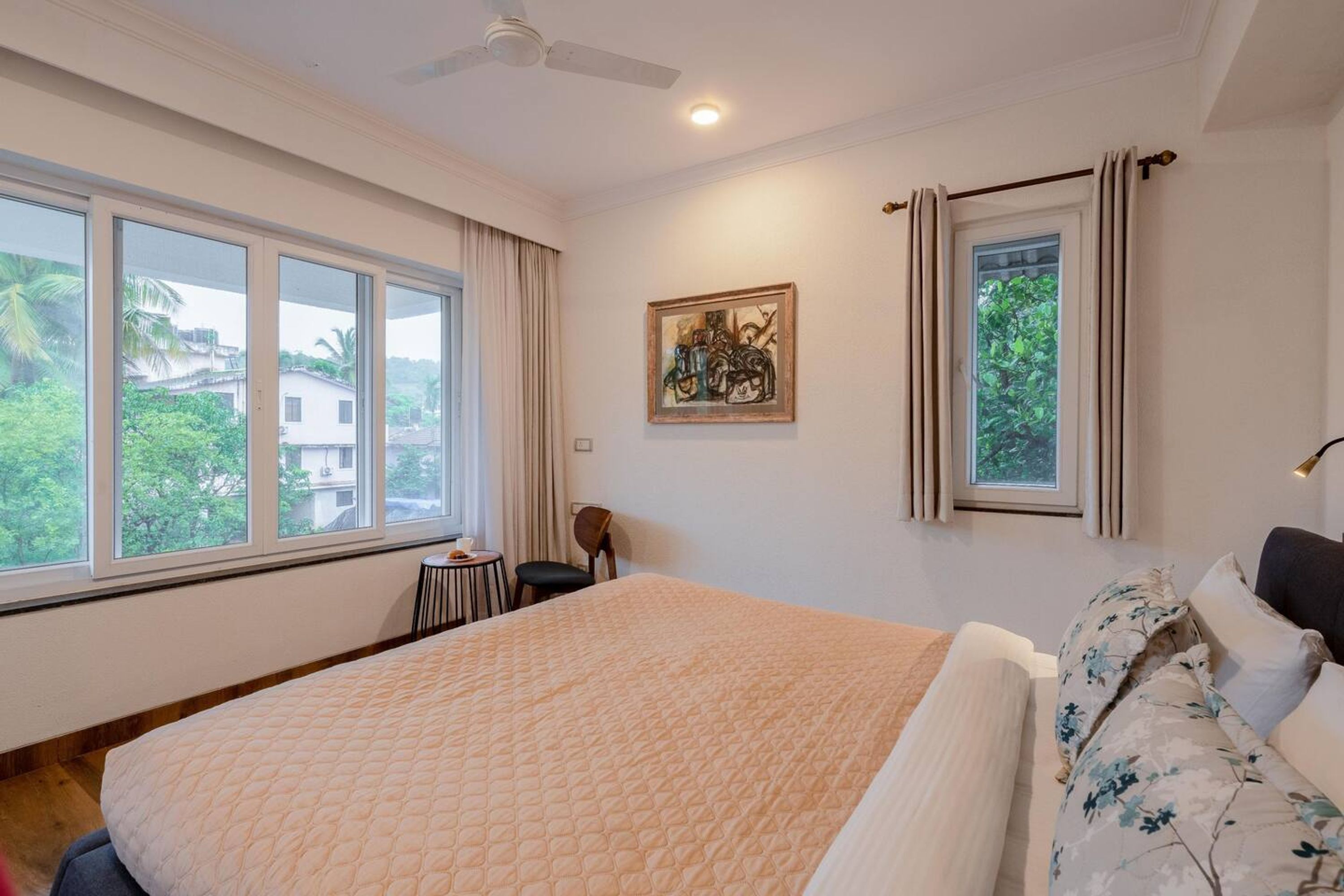 Une chambre avec un grand lit, un ventilateur de plafond et une fenêtre avec des rideaux.