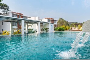 Un hôtel moderne doté d’une piscine, d’un espace extérieur couvert et d’une cascade décorative.