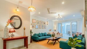 A spacious living room with a teal sofa, a wooden coffee table, and a large mirror on the wall.