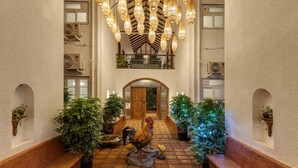 A hotel lobby with a central staircase, potted plants, and a decorative rooster statue. - Villa Verona by Hireavilla 6BR With Pool in Parra (Parra)