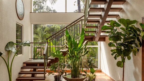 A staircase with wooden steps and metal railings, surrounded by various potted plants. - Villa Verona by Hireavilla 6BR With Pool in Parra (Parra)