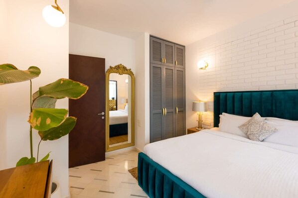 Een slaapkamer met een bed, een kledingkast, een spiegel en een plant.