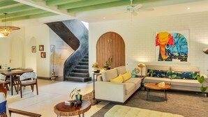 Un amplio espacio de estar con una escalera, un sofá, una mesa de centro y una mesa de comedor.