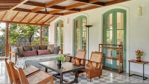 Un área de estar al aire libre techada con una mesa y sillas de madera, un sofá con cojines y vistas al exterior.