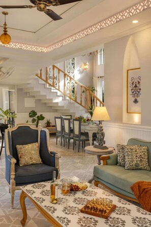 A spacious living room with a grand staircase, a dining area, and a cozy seating arrangement.