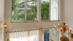 A spacious room with large windows, a wooden staircase, and a chandelier. - Villa Jaanzu - 4bhk With Private Pool in Saligao (Calangute)
