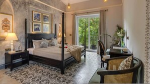 A bedroom with a four-poster bed, a nightstand, a chair, a table, and a view of greenery through the window. - Villa Jaanzu - 4bhk With Private Pool in Saligao (Calangute)
