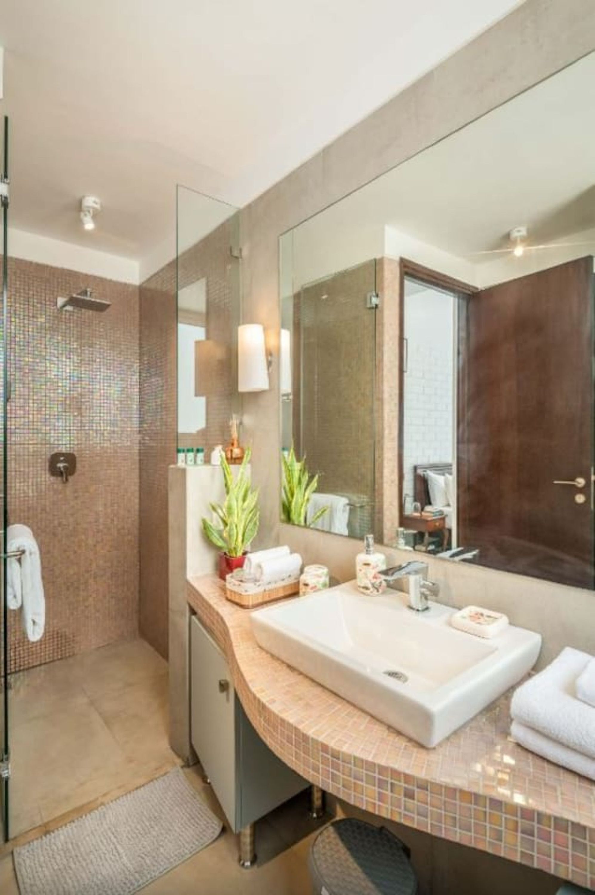 Un baño moderno con un espejo grande, un lavamanos y una zona de ducha.
