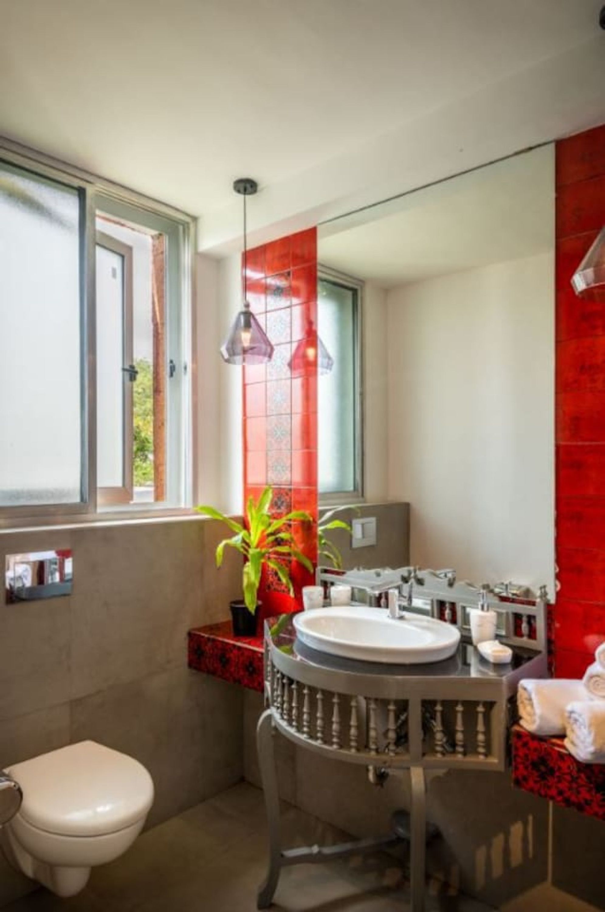 A bathroom with a toilet, sink, and a potted plant.