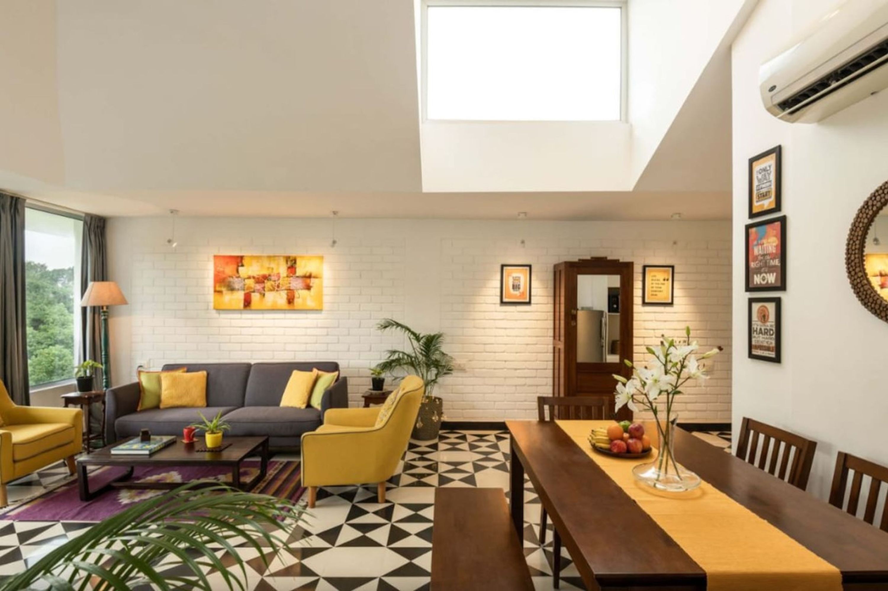 A modern living room with a sofa, chairs, a dining table, and a geometric patterned floor.