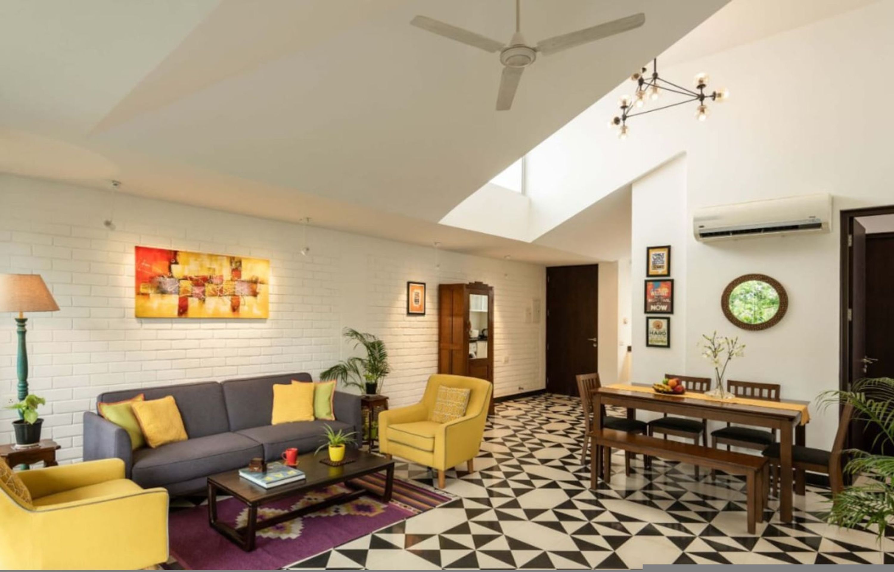 A modern living room with a sofa, armchairs, a coffee table, and a dining area with a table and chairs.