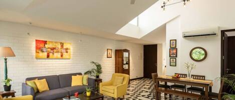 A modern living room with a sofa, armchairs, a coffee table, and a dining area with a table and chairs.
