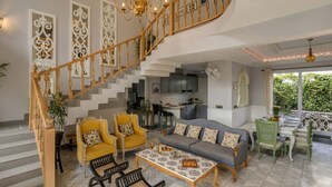 A spacious living area with a staircase, a dining area, and a kitchen. - The Hornbill Villa - 3bhk With Pvt Pool in Saligao (Calangute)