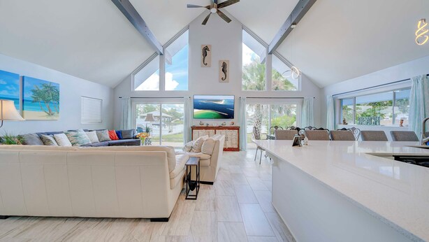 A spacious living area with a large sofa, a dining table, and a kitchen area with a long counter. - Dolphin Days Lagoon Escape (Panama City)