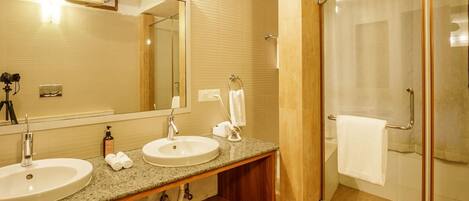 A bathroom with two sinks, a large mirror, and a glass-enclosed shower area.