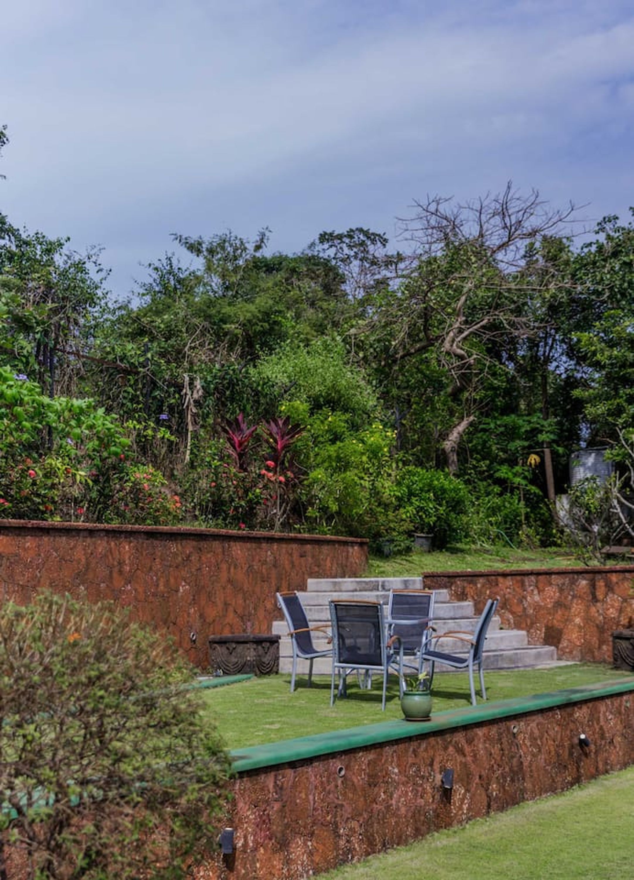 A patio with outdoor furniture and a view of a lush garden.
