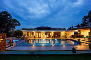 Ein modernes Haus mit Swimmingpool, überdachter Terrasse und einem gepflegten Garten.