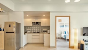A modern kitchen with white cabinets, a stainless steel refrigerator, and patterned backsplash tiles. - Spacious 3BR Apartment With Pool in Candolim (Candolim)
