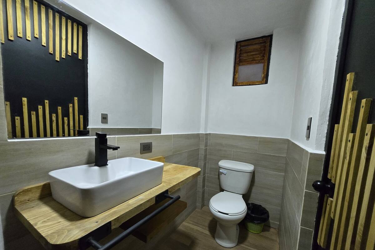 A modern bathroom with a rectangular sink, a toilet, and a small window.