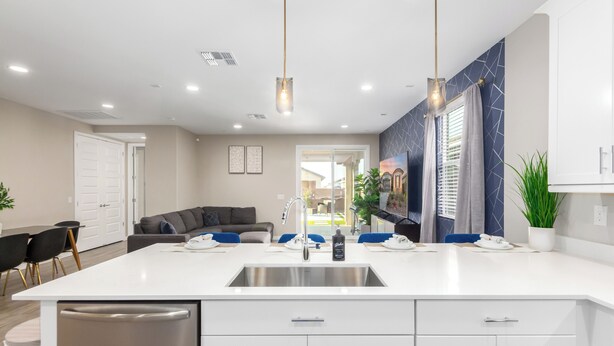 Una cocina moderna con una isla central, electrodomésticos de acero inoxidable e iluminación colgante.