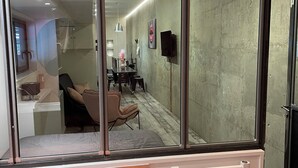 Ein modernes Interieur mit einem großen Fenster, einem Heizkörper und einem Essbereich, der durch das Glas sichtbar ist.