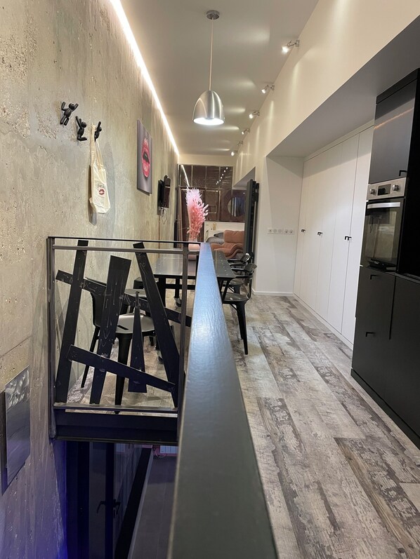 A modern kitchen with a wooden floor, white cabinets, and a black oven. - Fashion Lodge (Paris)
