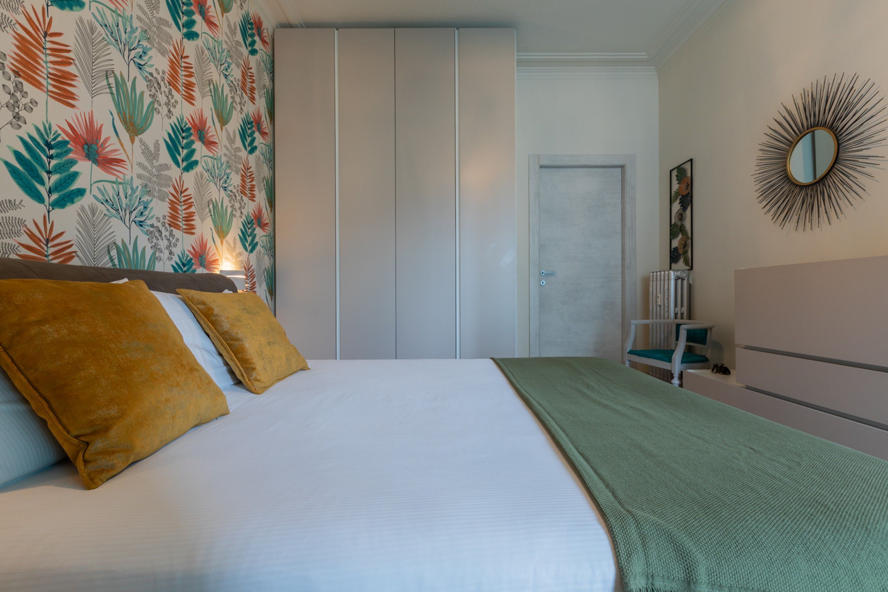 A bedroom with a bed, a wardrobe, a mirror, and a radiator.